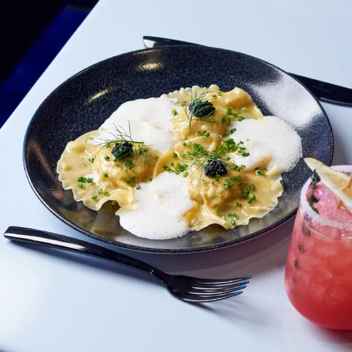 A plate of pasta with a glass of wine on it.