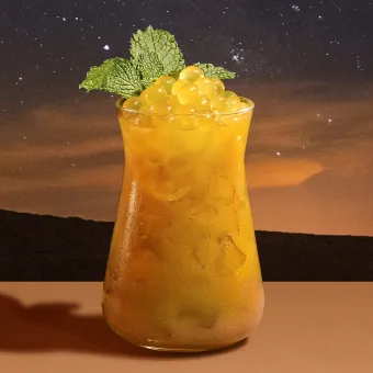 An orange drink with a mint leaf on top.