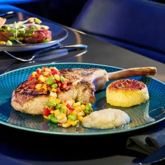 A plate of chicken with vegetables and bread on a blue plate.